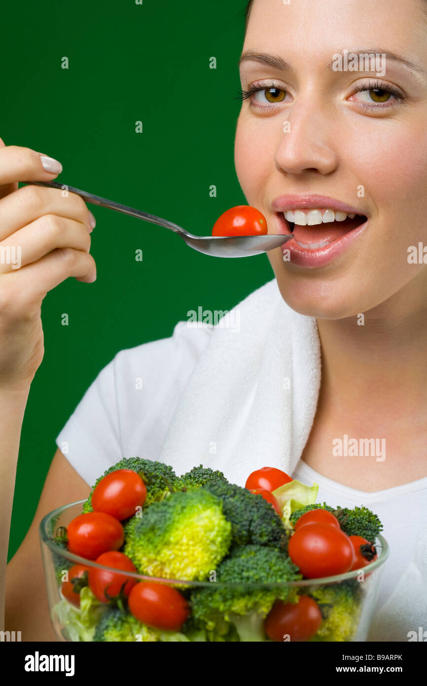 Donna di mangiare pomodoro e insalata di broccoli Foto Stock