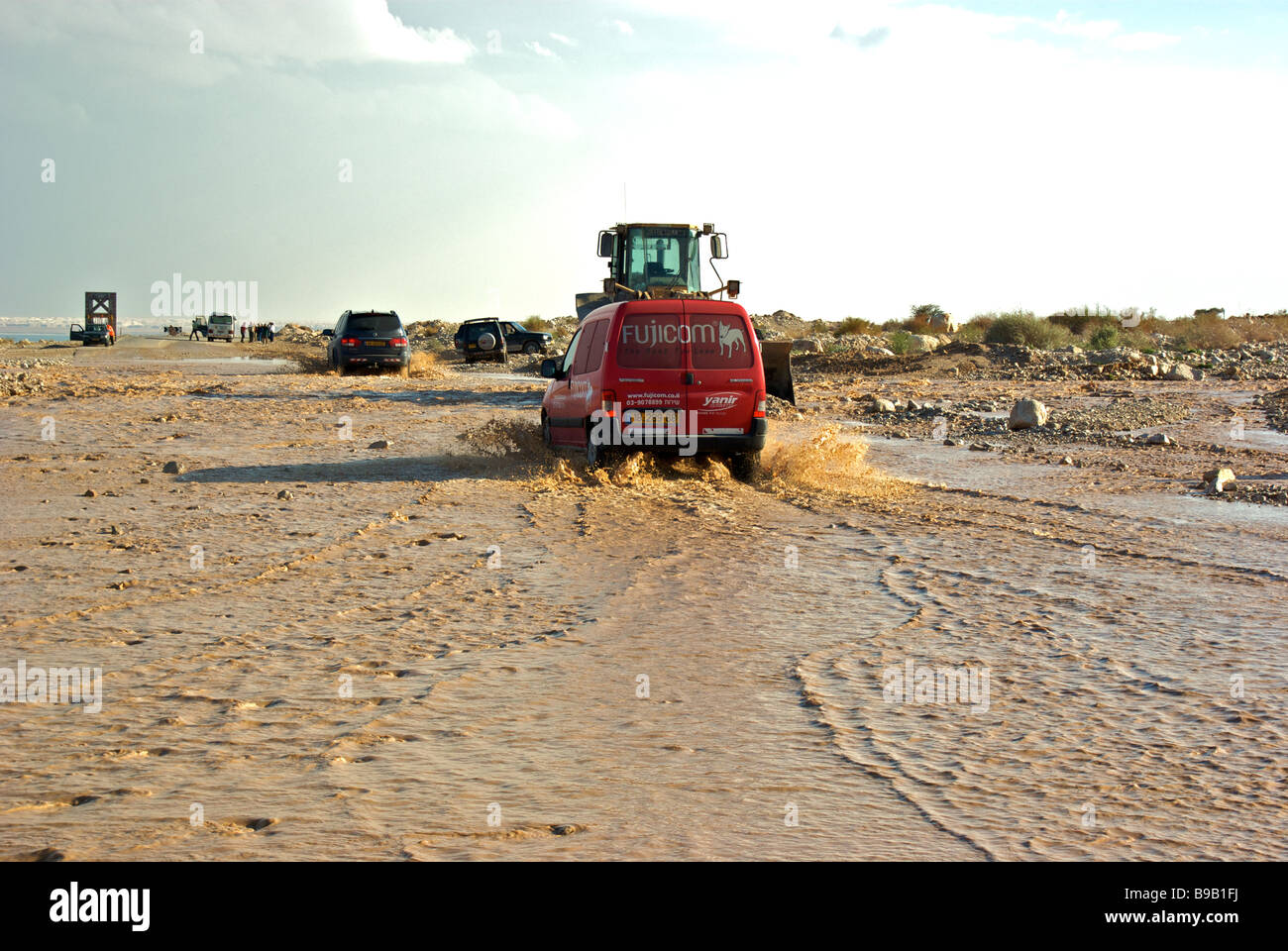 Furgoni schizzi attraverso acque di inondazione autostrada di copertura 90 alla città turistica di Ein Bokek sul Mar Morto Foto Stock