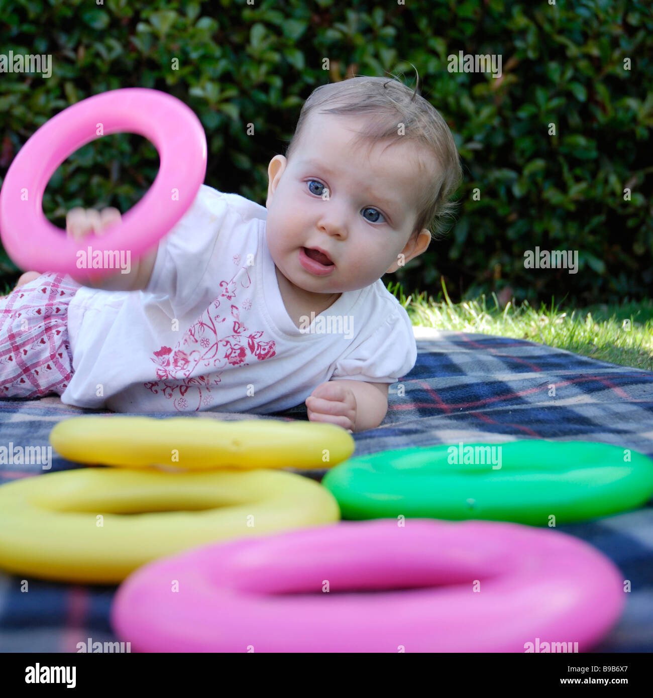Otto mesi a giocare fuori con colorati cerchi in plastica Foto Stock