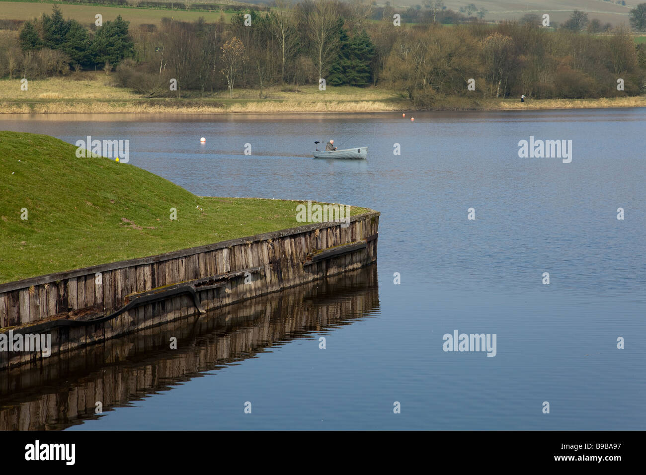 Lone pescatore a mosca in una barca sul loch Foto Stock