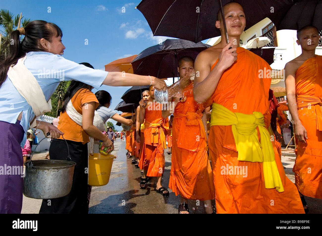 Donne gettare acqua sul monaco durante il bun pi mai Lao anno nuovo Foto Stock