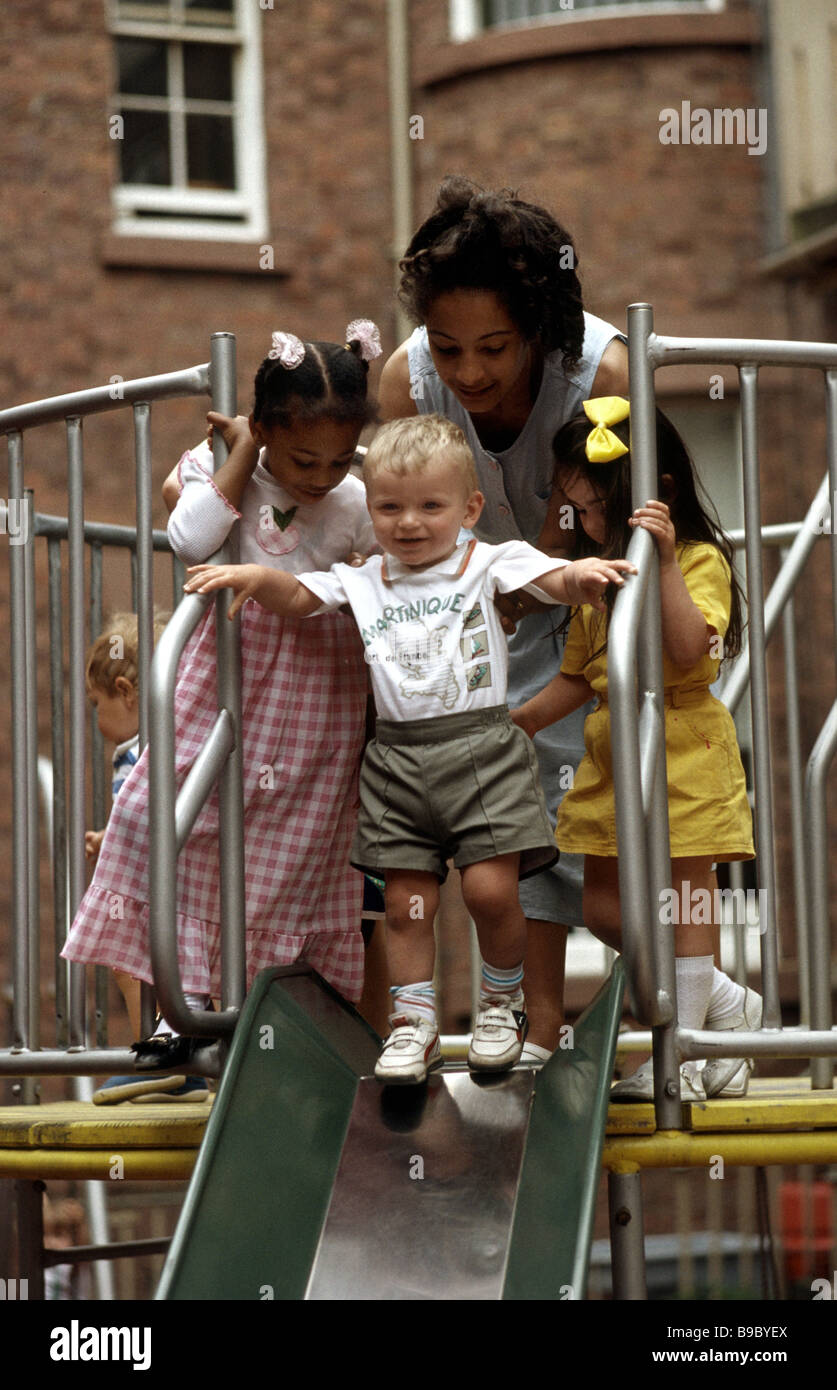 Bambini della scuola materna con insegnante su un telaio di arrampicata nel parco giochi a scuola Foto Stock