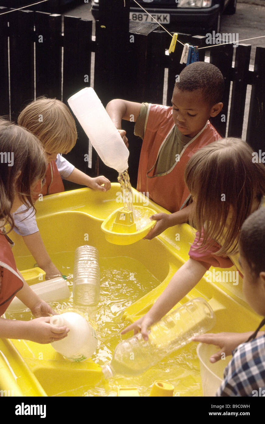 La scuola materna di bambini che giocano con acqua nel parco giochi Foto Stock