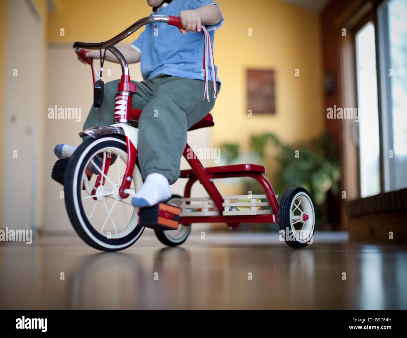 Bambino a cavallo di un triciclo intorno alla casa Foto Stock