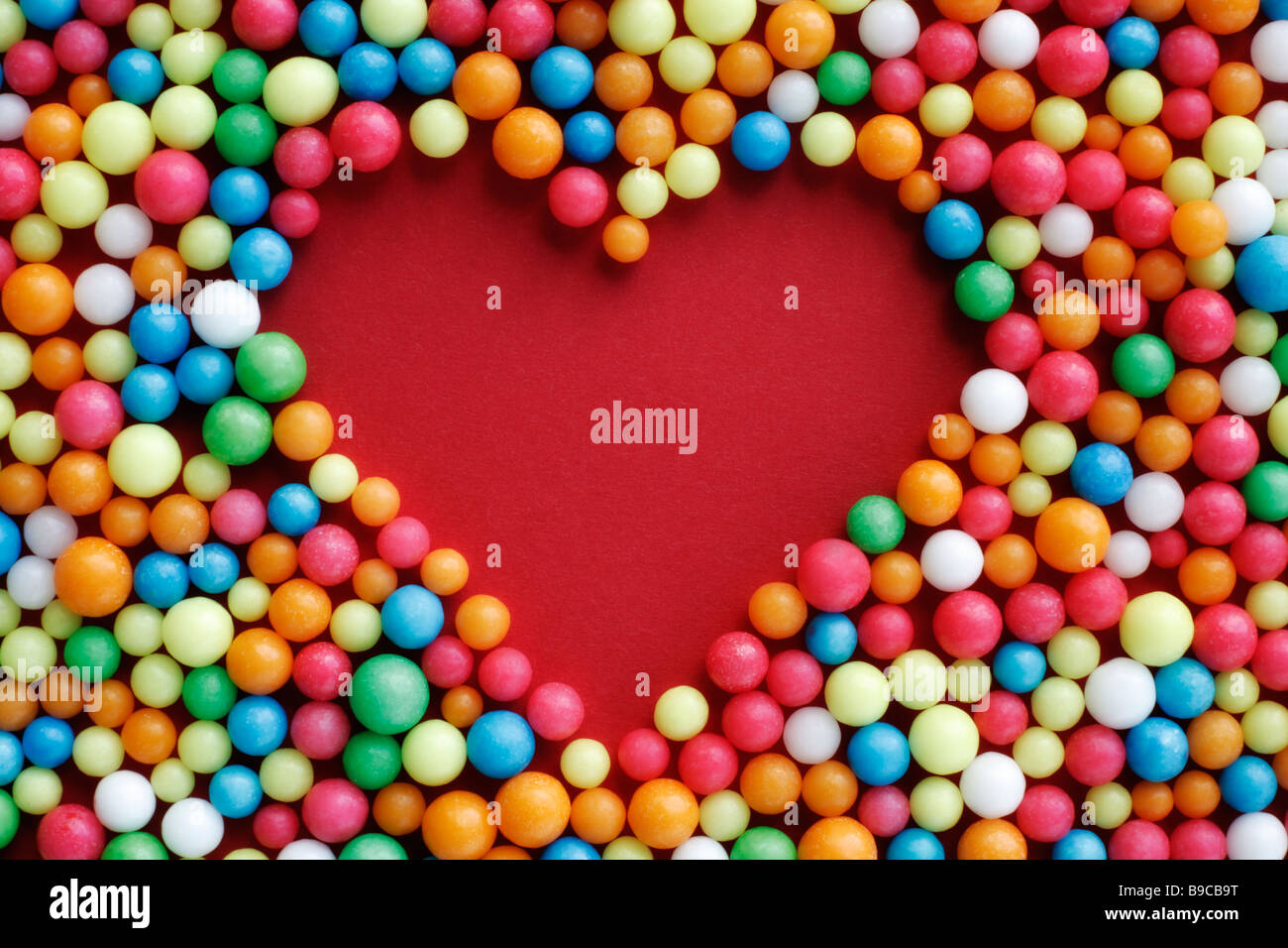 Herz aus Liebesperlen auf einfarbigen Untergrund Foto Stock