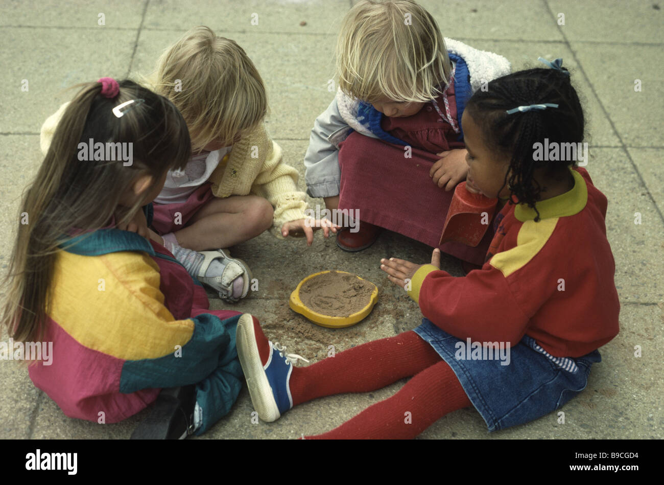 La scuola materna di ragazze gioca con la sabbia nel parco giochi Foto Stock