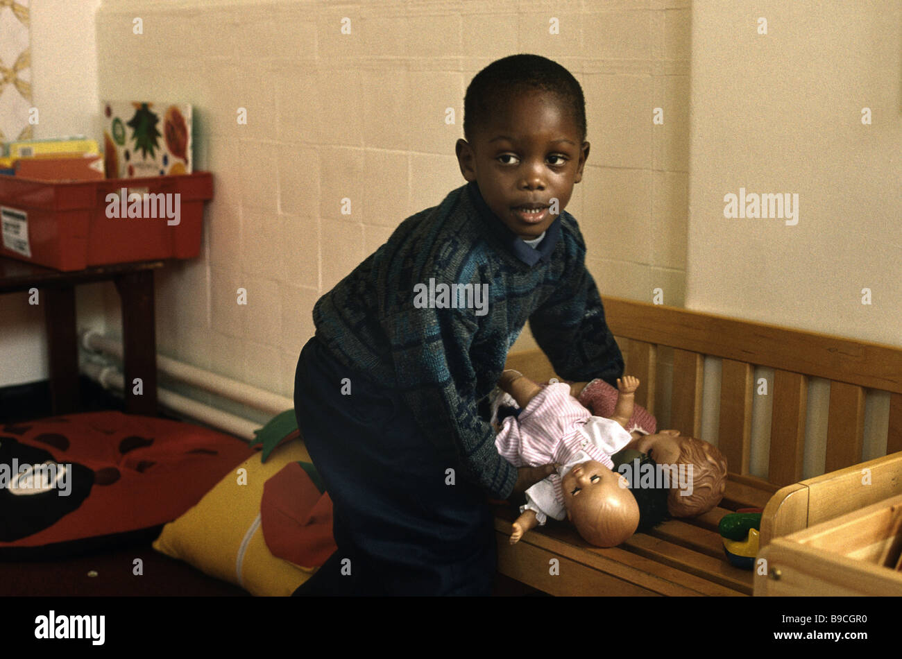 Black Boy a giocare con le bambole nella scuola materna Foto Stock