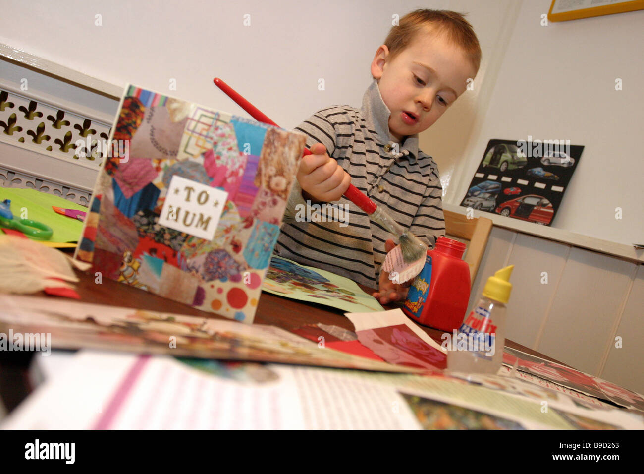 Un giovane bambino tagliare e incollare carta fatta a mano Foto Stock
