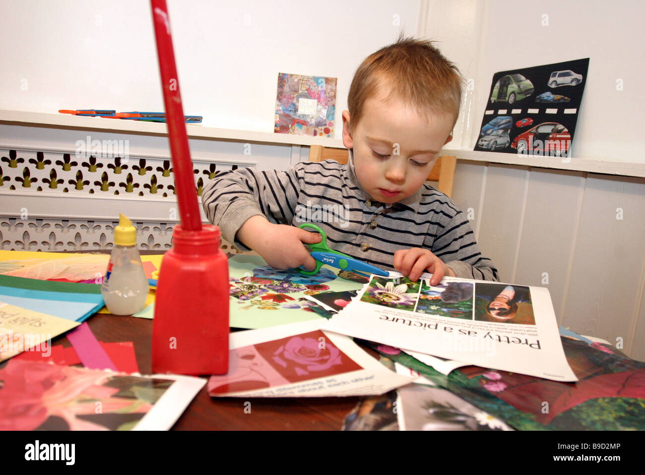 Un giovane bambino tagliare e incollare carta fatta a mano Foto Stock