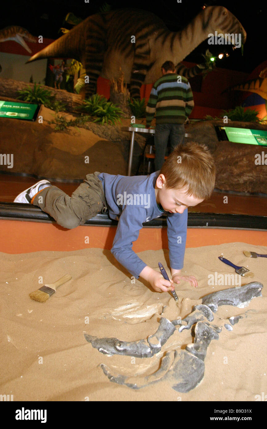 Bambini imparare circa archeologia dalla copertura delle Nazioni Unite ossa di dinosauro presso un museo della scienza. Foto Stock