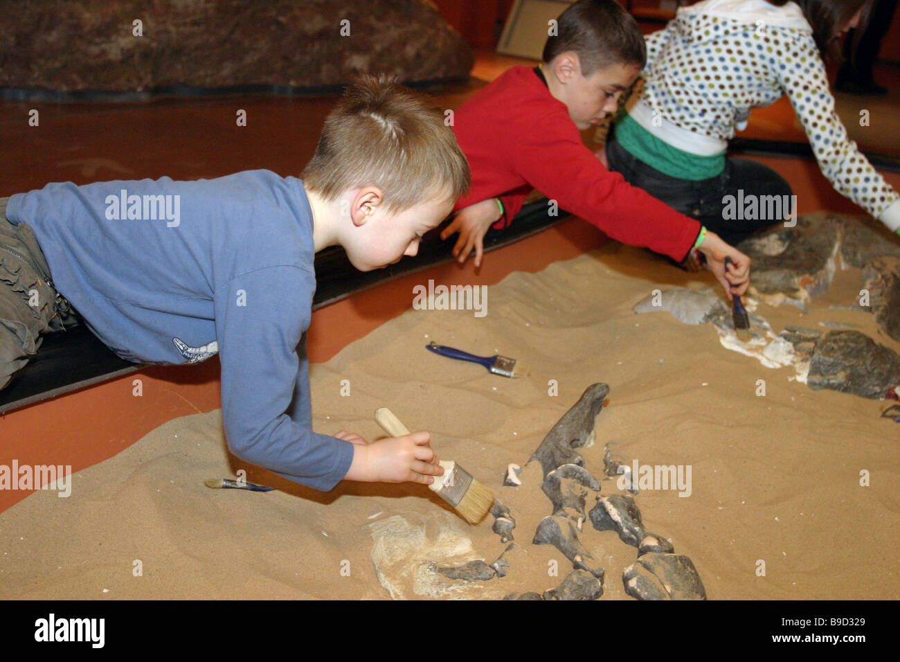 Bambini imparare circa archeologia dalla copertura delle Nazioni Unite ossa di dinosauro presso un museo della scienza. Foto Stock