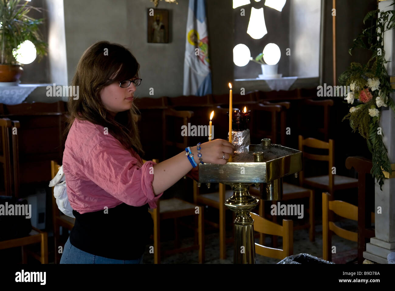 Giovane donna candela di illuminazione alla Chiesa di Metamorphis Vathi Samos Grecia Foto Stock