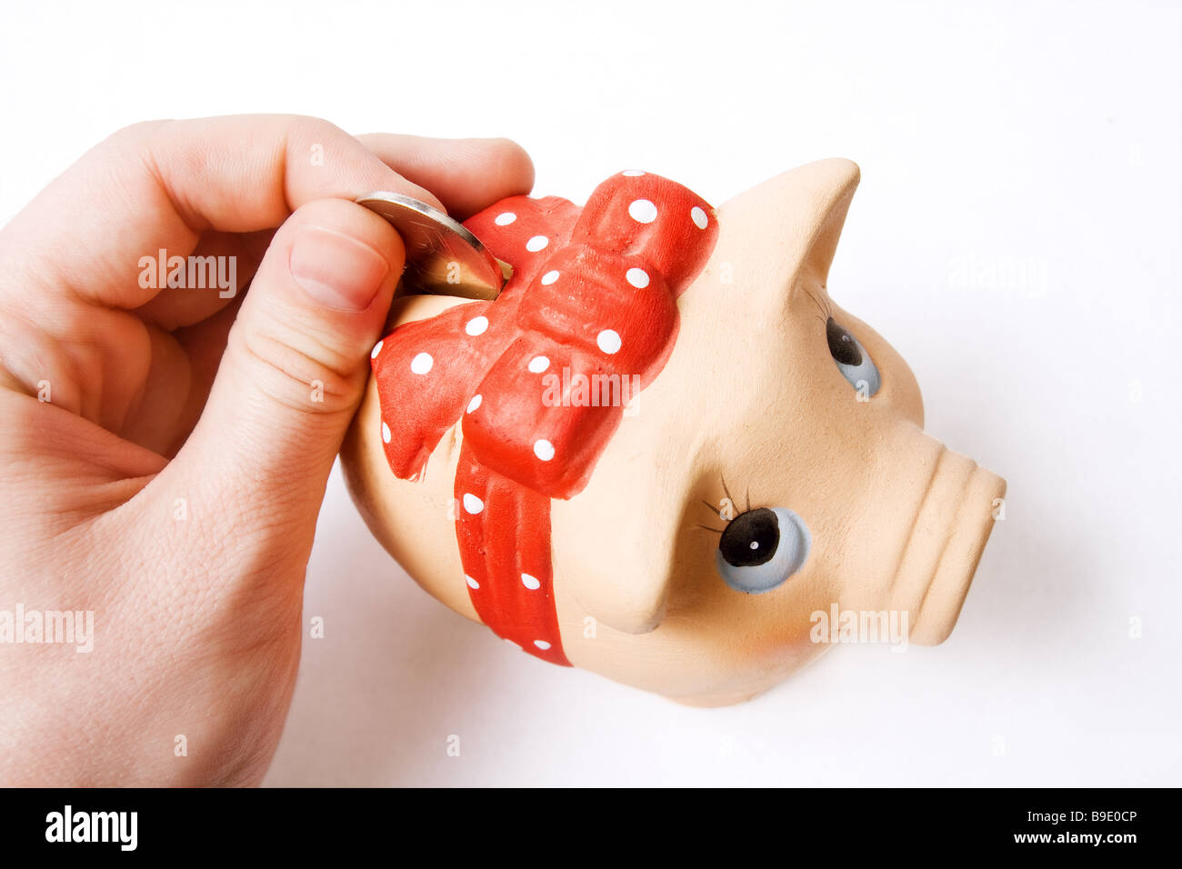 Risparmio di denaro concetto moneta inserita nel grazioso salvadanaio Foto Stock