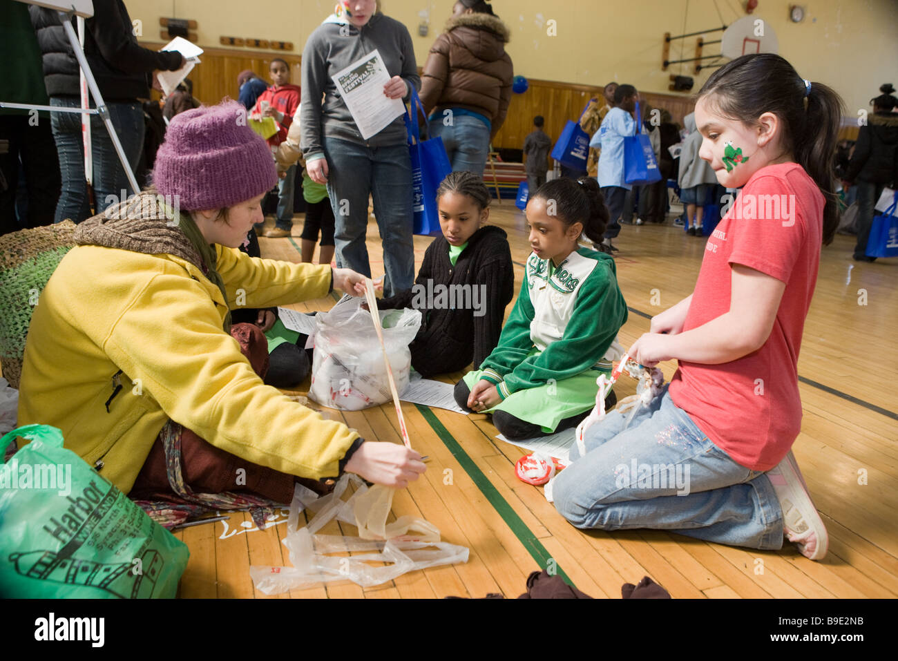 Donna insegnare ai bambini come crochet utilizzando materiale plastico riciclabile in una Fiera Verde a Syracuse, New York Foto Stock