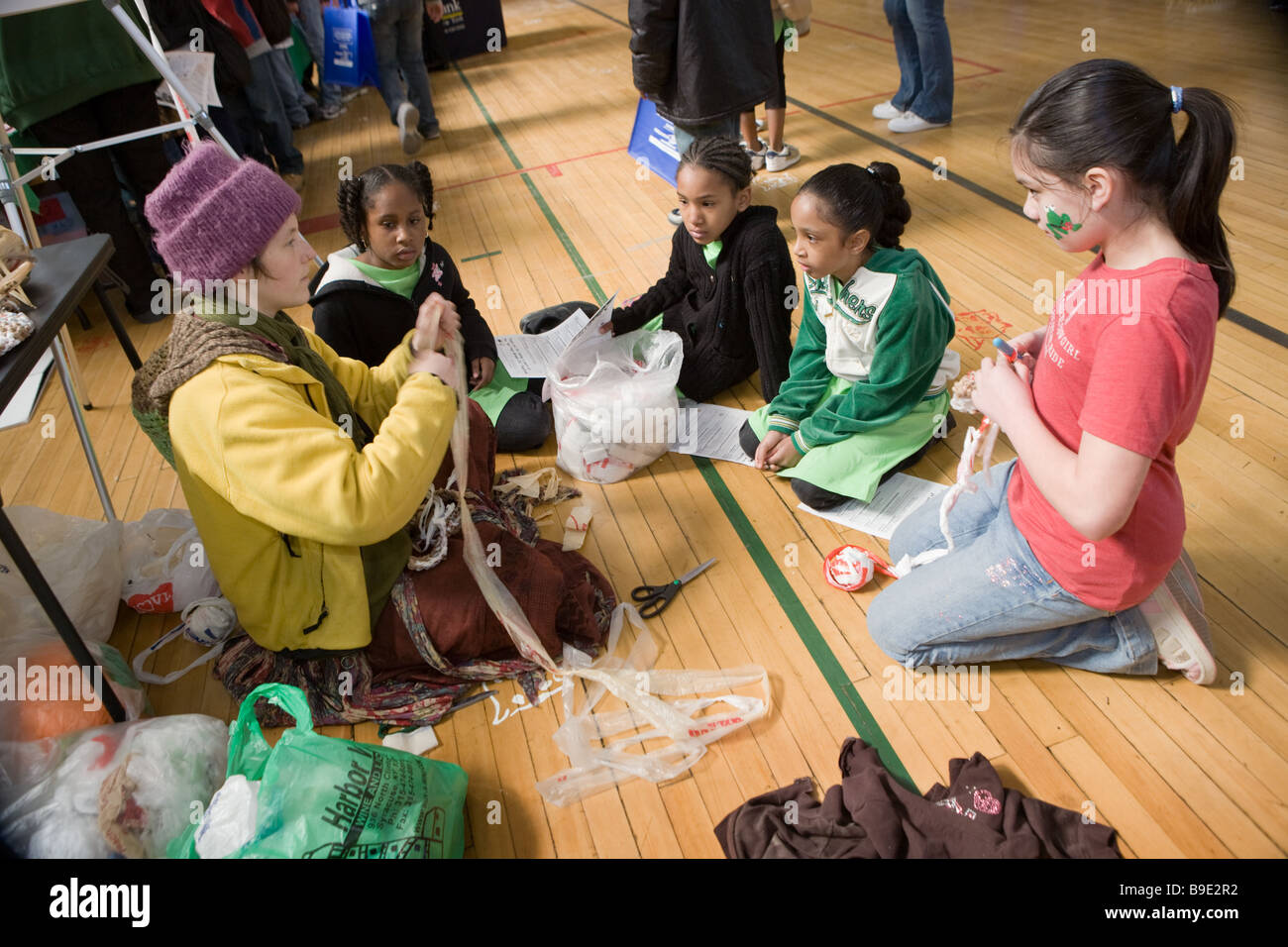 Donna insegnare ai bambini come crochet utilizzando materiale plastico riciclabile in una Fiera Verde a Syracuse, New York Foto Stock