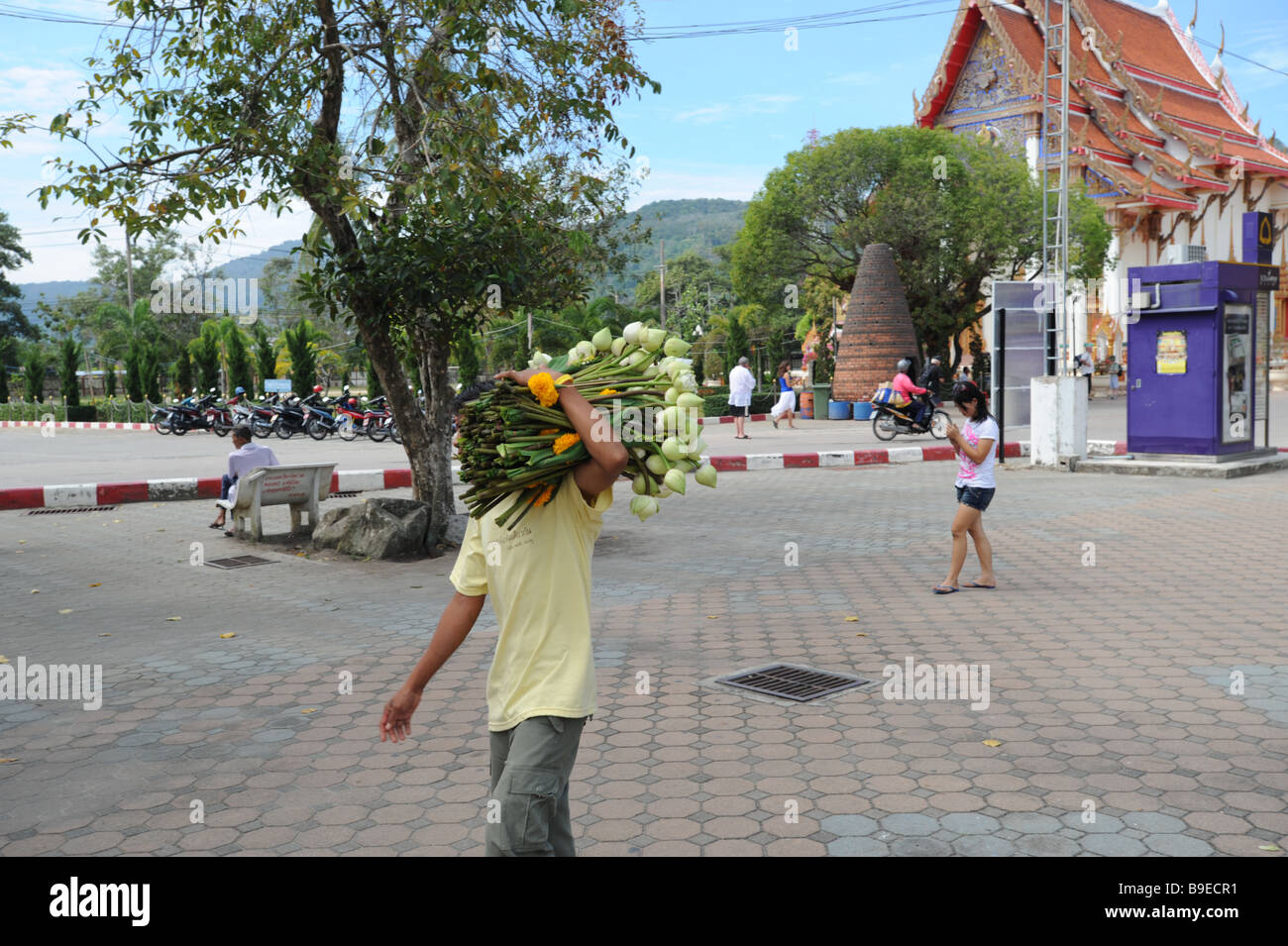 Uomo tailandese consegna fiori in motivi di Wat Chalong buddhisti tempio Phuket Thailandia Foto Stock