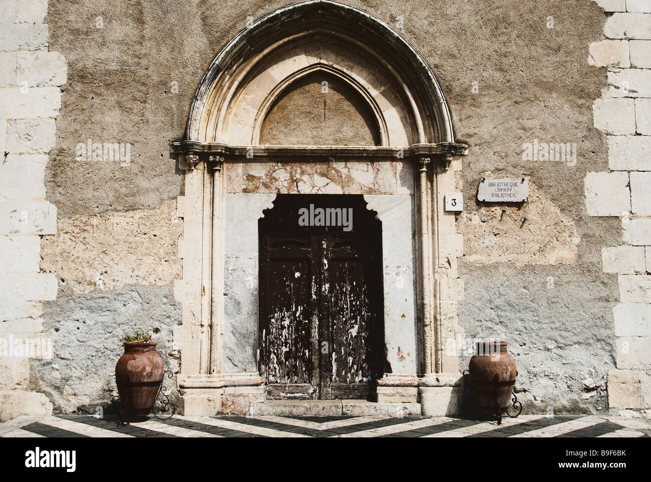 Antica porta in legno che conduce alla libreria in Tamormina, Sicilia ( Italia ) con due vasi, uno su ciascun lato della porta. Foto Stock