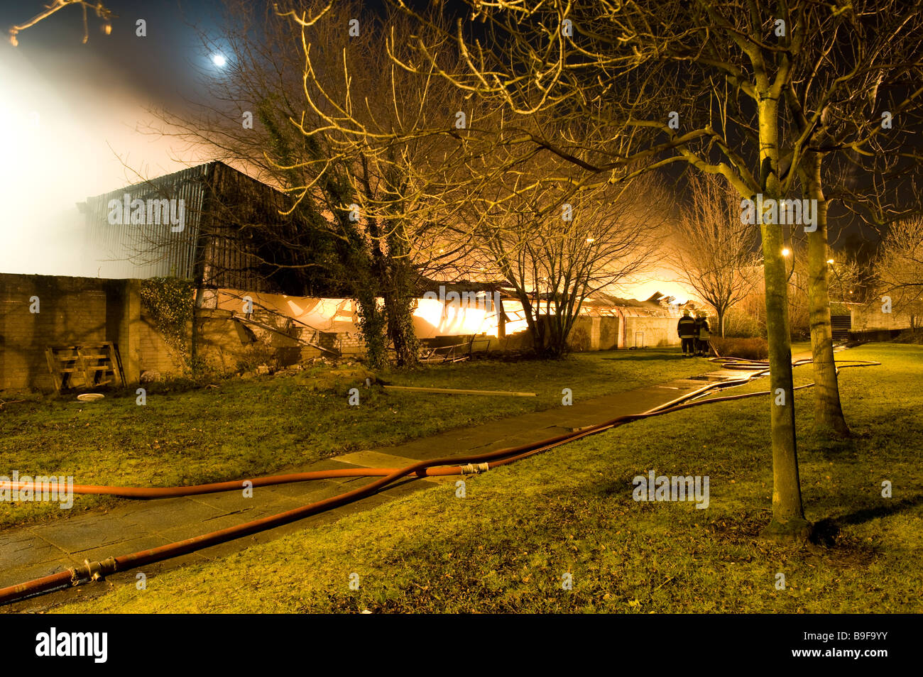 Grande magazzino di fabbrica sul fuoco di notte con la luna in background Foto Stock