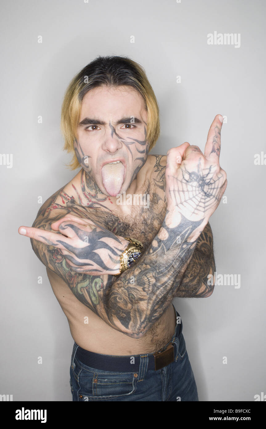 L'uomo giovane seriamente il corpo superiore liberamente tatuaggi 'Stinkefinger' mostrano la linguetta gesto semi-ritratto di persone faccia-tattoo tatuaggi Foto Stock