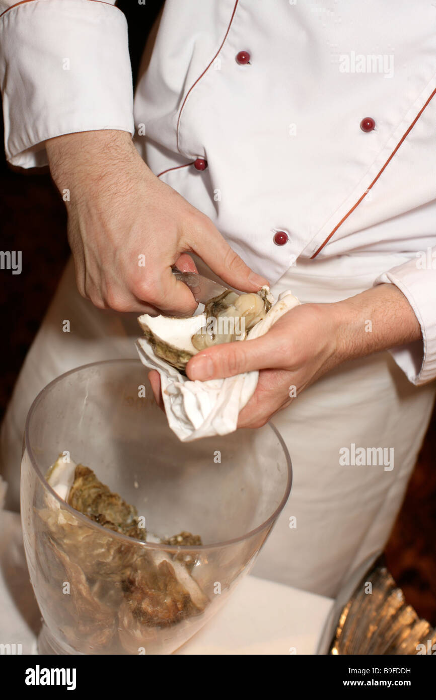 Le mani dello chef preparazione delle conchiglie dei pellegrini Foto Stock