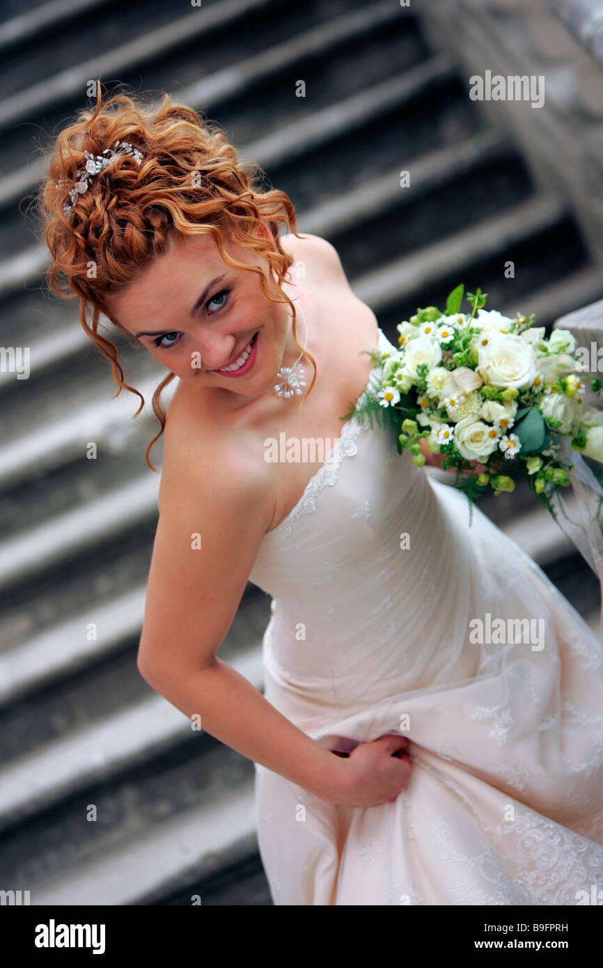 Sposa sorridente con bouquet a piedi giù per le scale Foto Stock