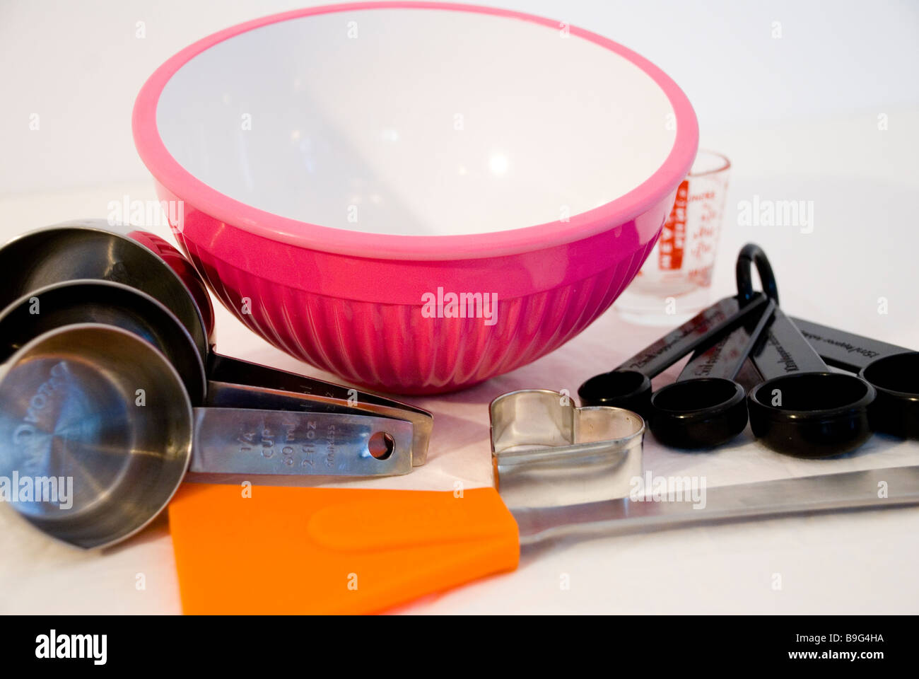 Selezione di pesatura e misurazione di utensili da cucina inc. rosa ciotola in Pyrex brocca & misurini su sfondo bianco Foto Stock