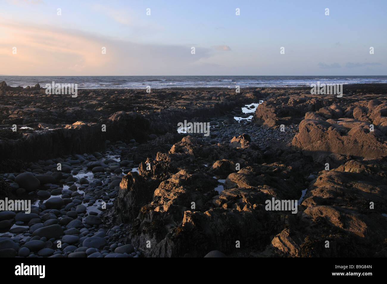 Luminosa luce della sera sulla spiaggia spiaggia di roccia Foto Stock