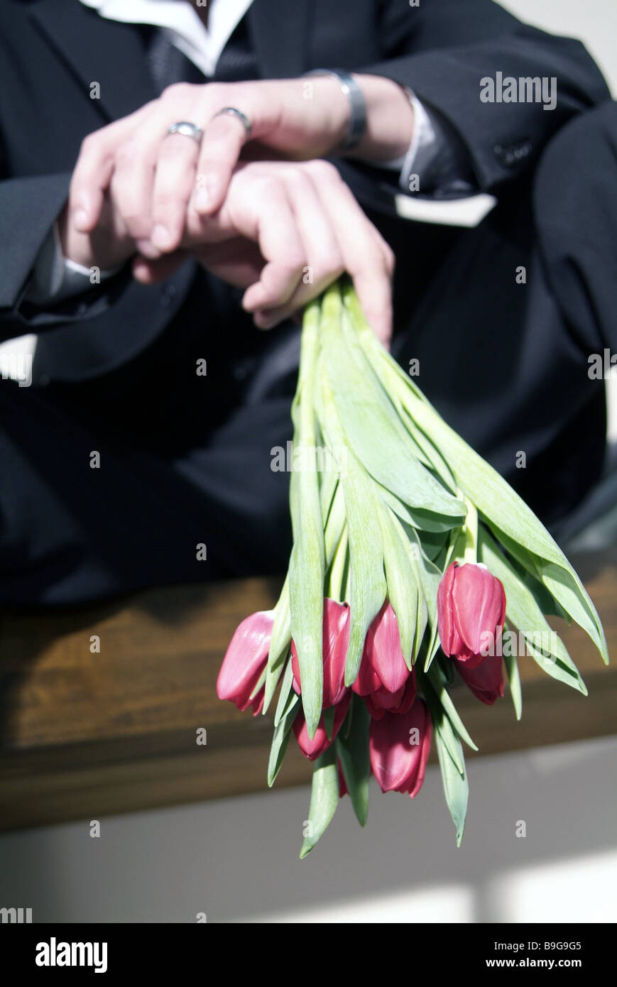 Siede l'uomo vestito di fiori bouquet attende brocciato persone serie rendezvous cadere in amore fiori tulipani tulip-bouquet Foto Stock