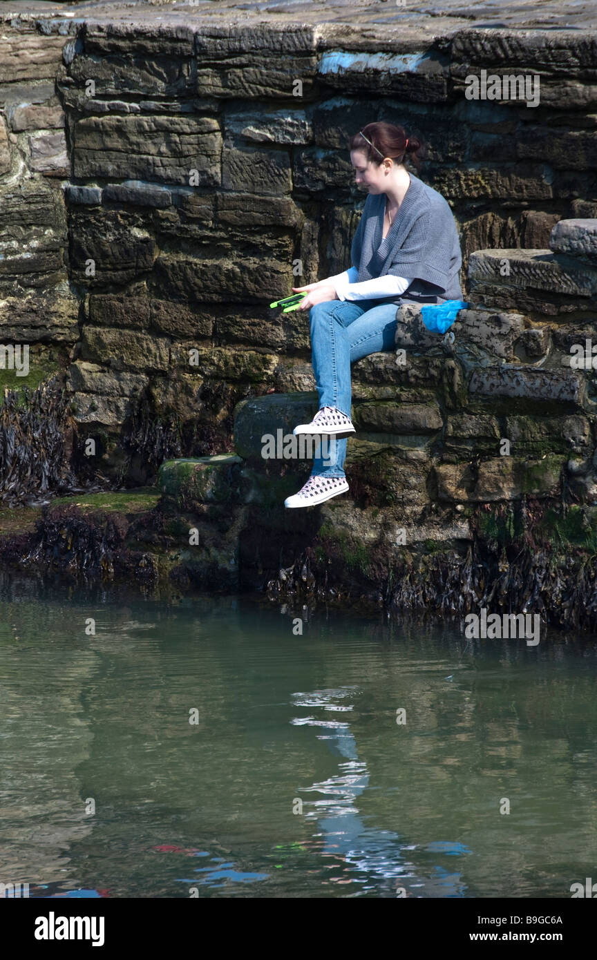 Una donna fishinh sulla parete del mare Foto Stock