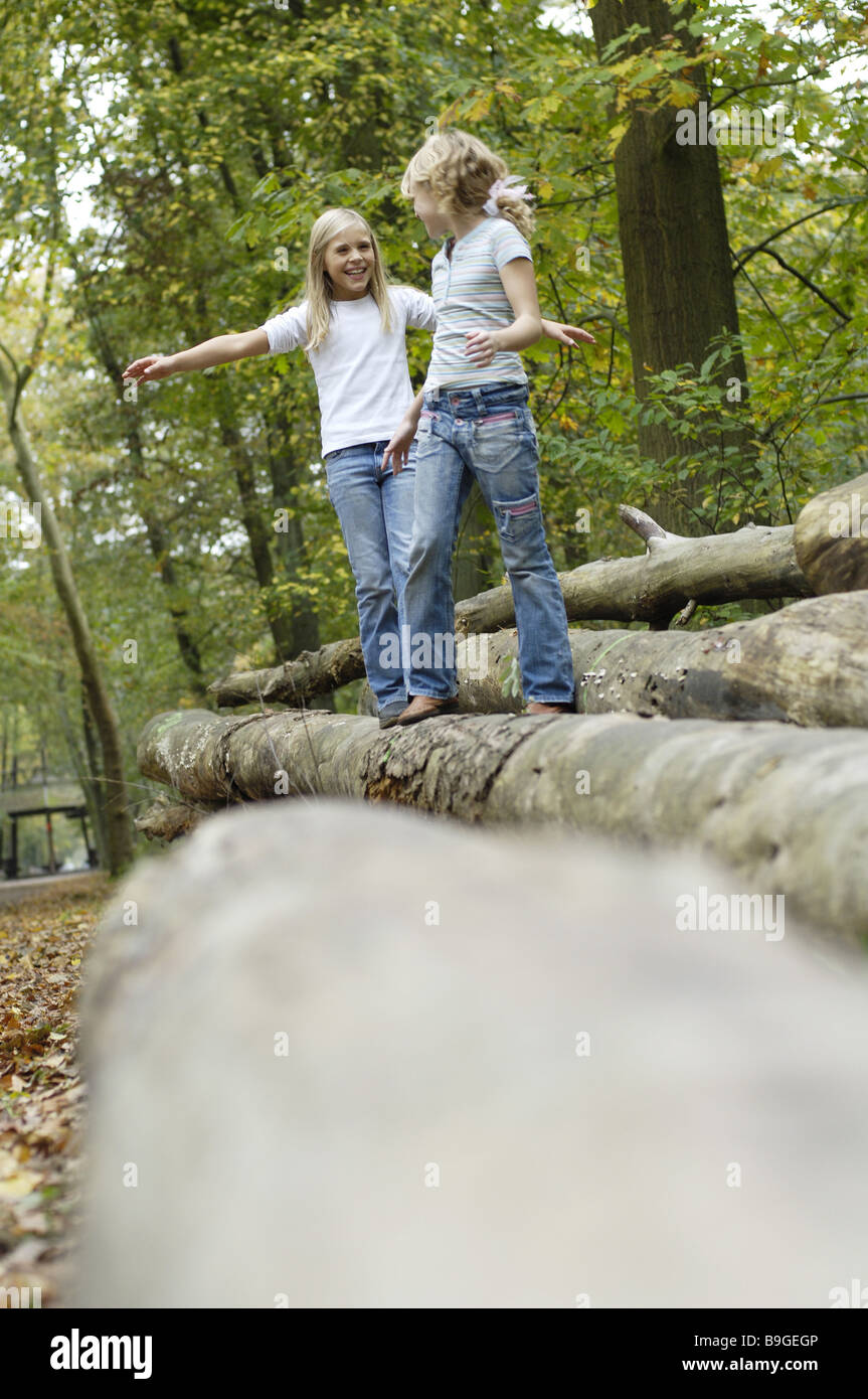 Bambini ragazza foresta due allegramente saldi log ride il contatto visivo amici 8-12 anni amici amicizia divertente gioco insieme la gioia Foto Stock