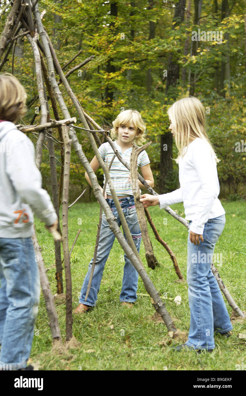 Bambini Ragazzi ragazza foresta rami giocare 8-12 anni costruire "tenda" amici gruppo tre amicizia divertente gioco insieme la creatività Foto Stock