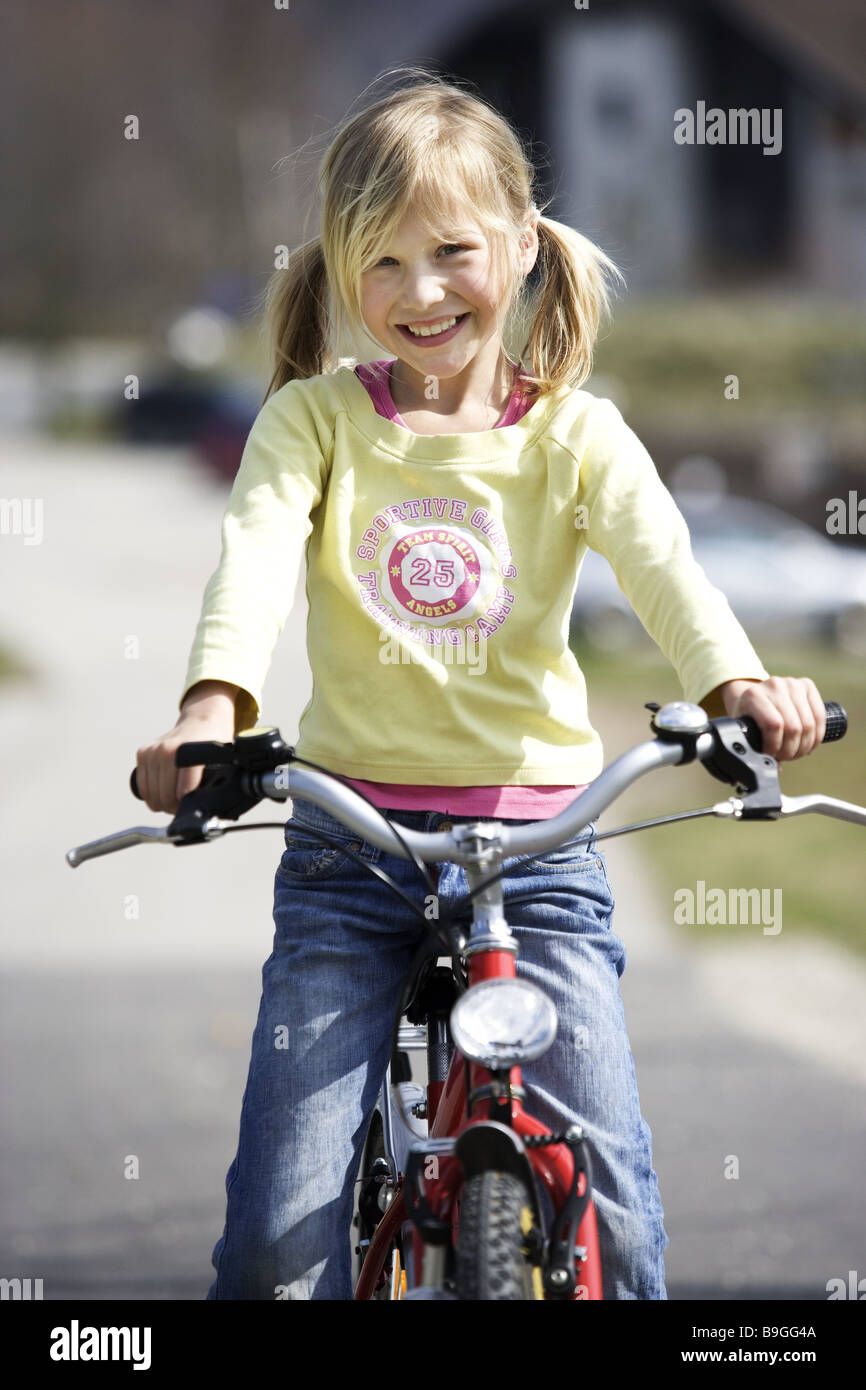 Ragazza bionda sorriso bike persone serie 8 anni bambino allegramente felicemente trecce infanzia spensieratezza gioia divertimento tempo libero Foto Stock
