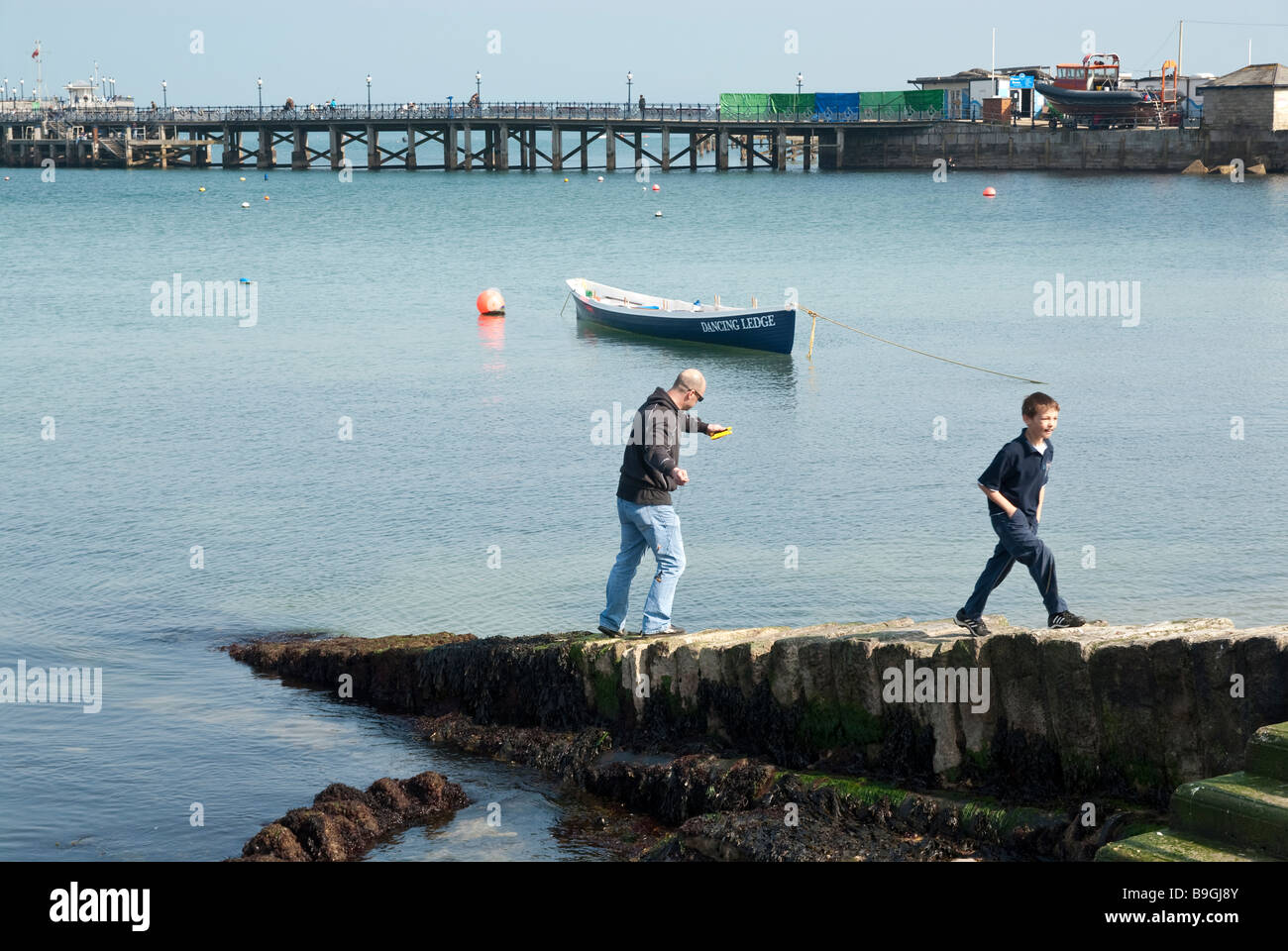 Padre e figlio di pesca al largo di frangiflutti a Swanage Foto Stock