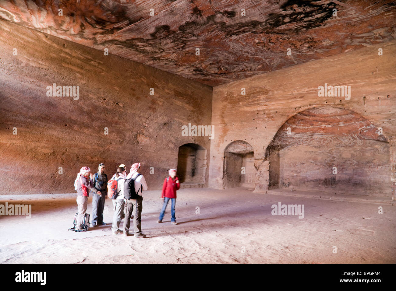 I turisti all'interno della tomba di URN, Petra Giordania Foto Stock