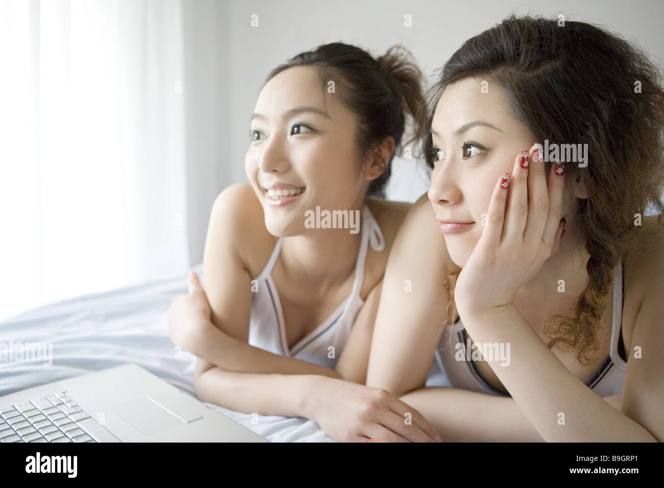 Due giovani donne sdraiato sul letto guardando al laptop Foto Stock
