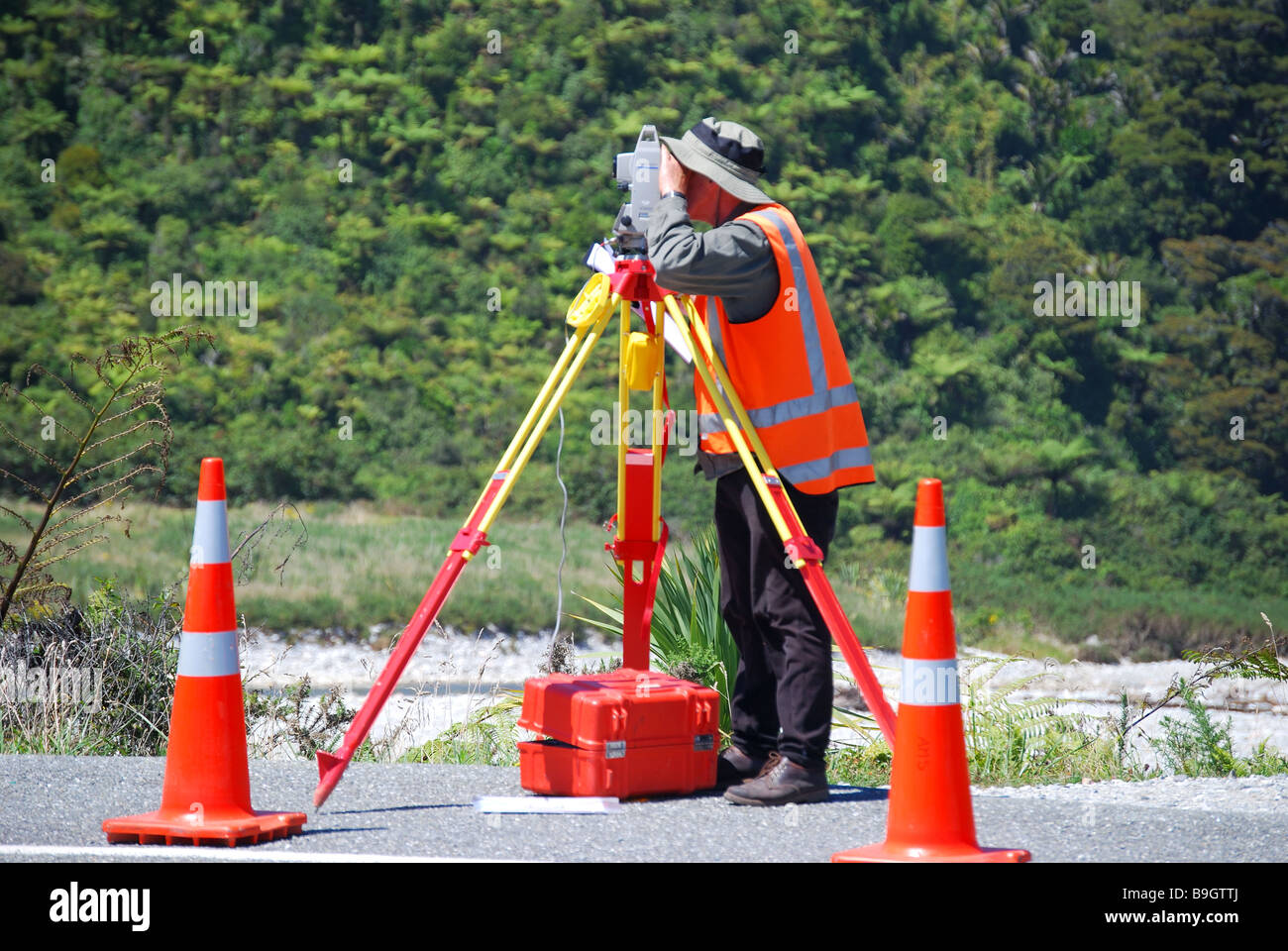 Geometra lavorando su strada con livello automatico, Paparoa National Park, West Coast, Isola del Sud, Nuova Zelanda Foto Stock