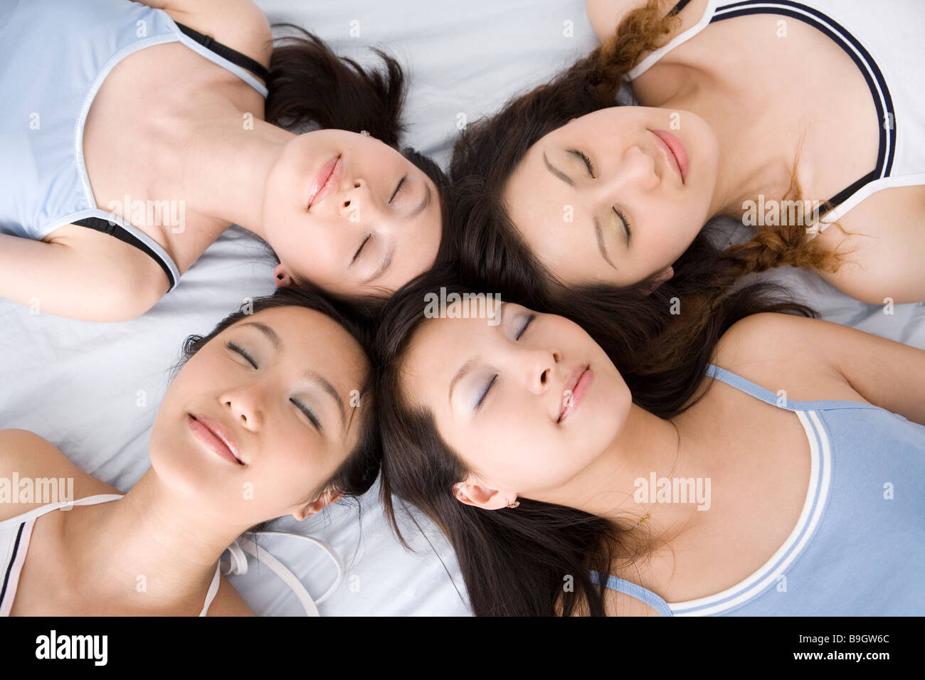 Quattro giovani donne giacente in cerchio sul letto Foto Stock
