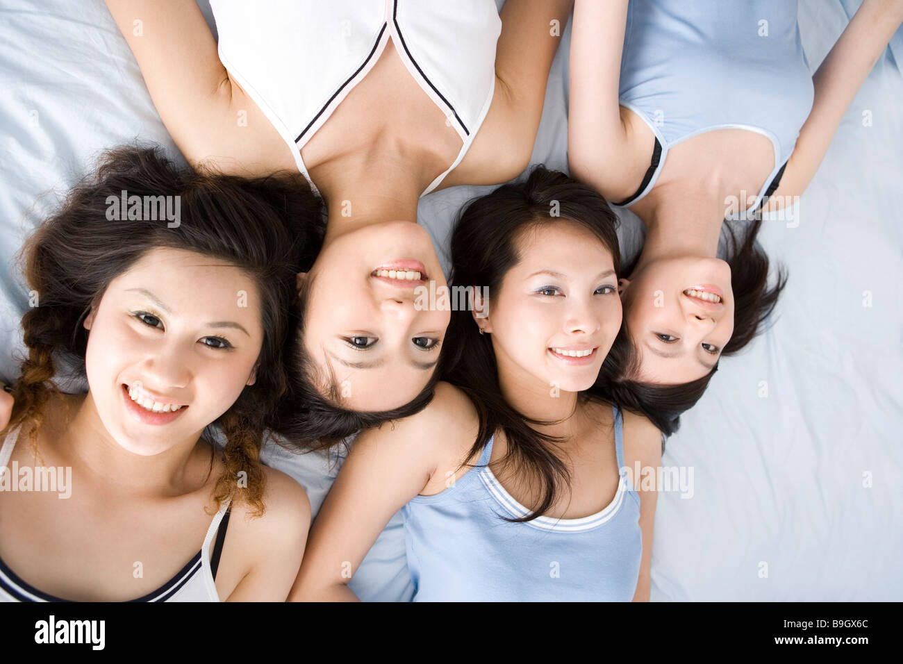 Quattro giovani donne giacente sul letto sorridente vista aerea Foto Stock