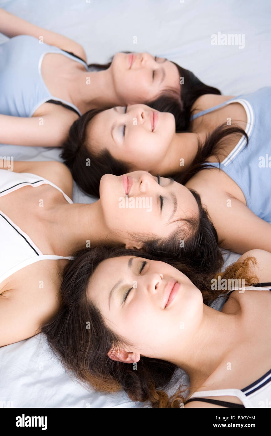Quattro giovani donne sdraiato sul letto Foto Stock
