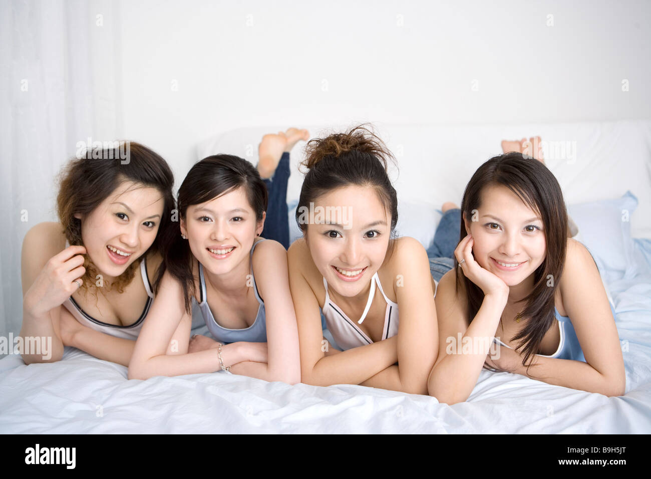 Quattro giovani donne sdraiato sul letto ritratto sorridente Foto Stock