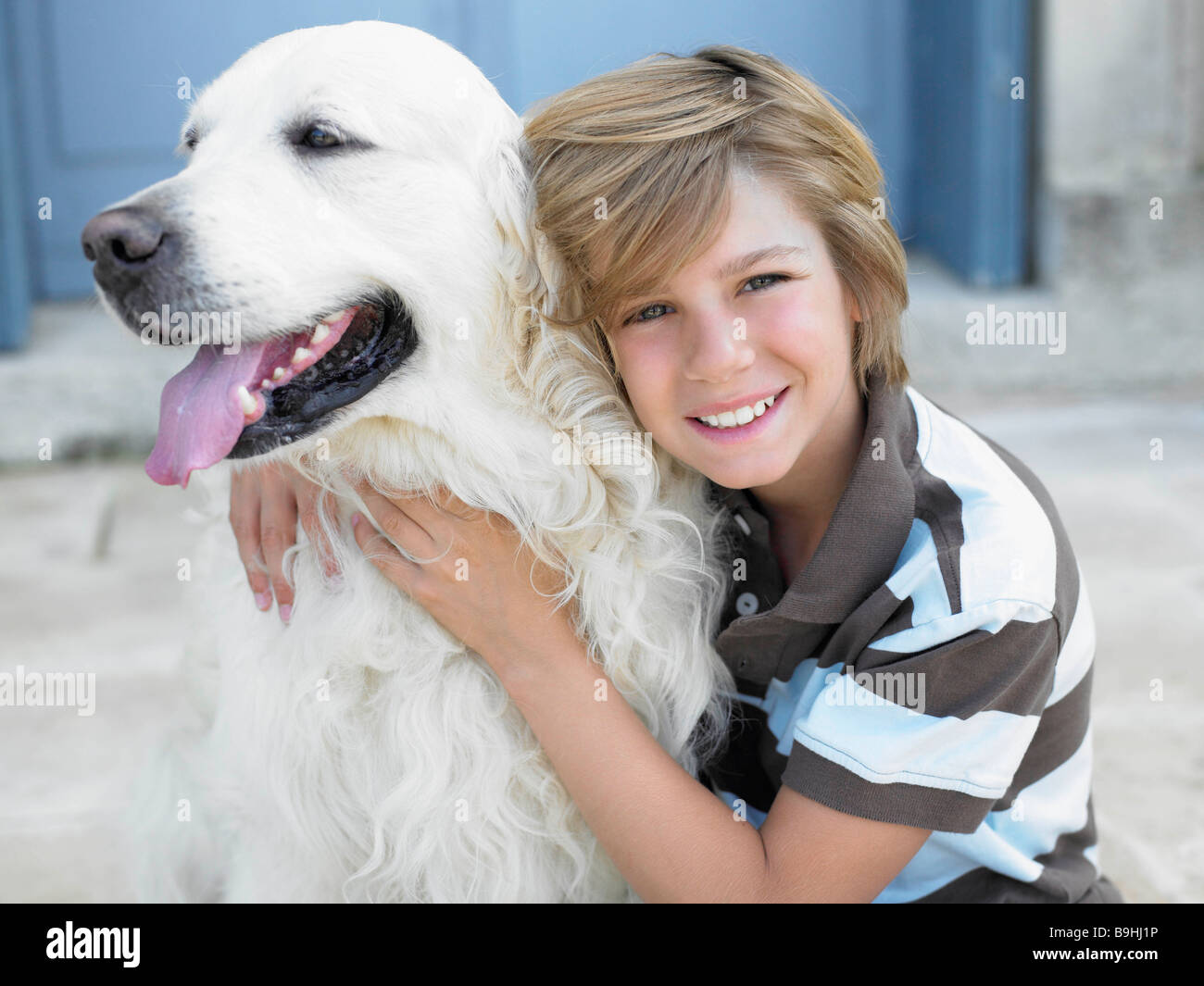 Ragazzo che sorride, con cane sul gradino della porta Foto Stock