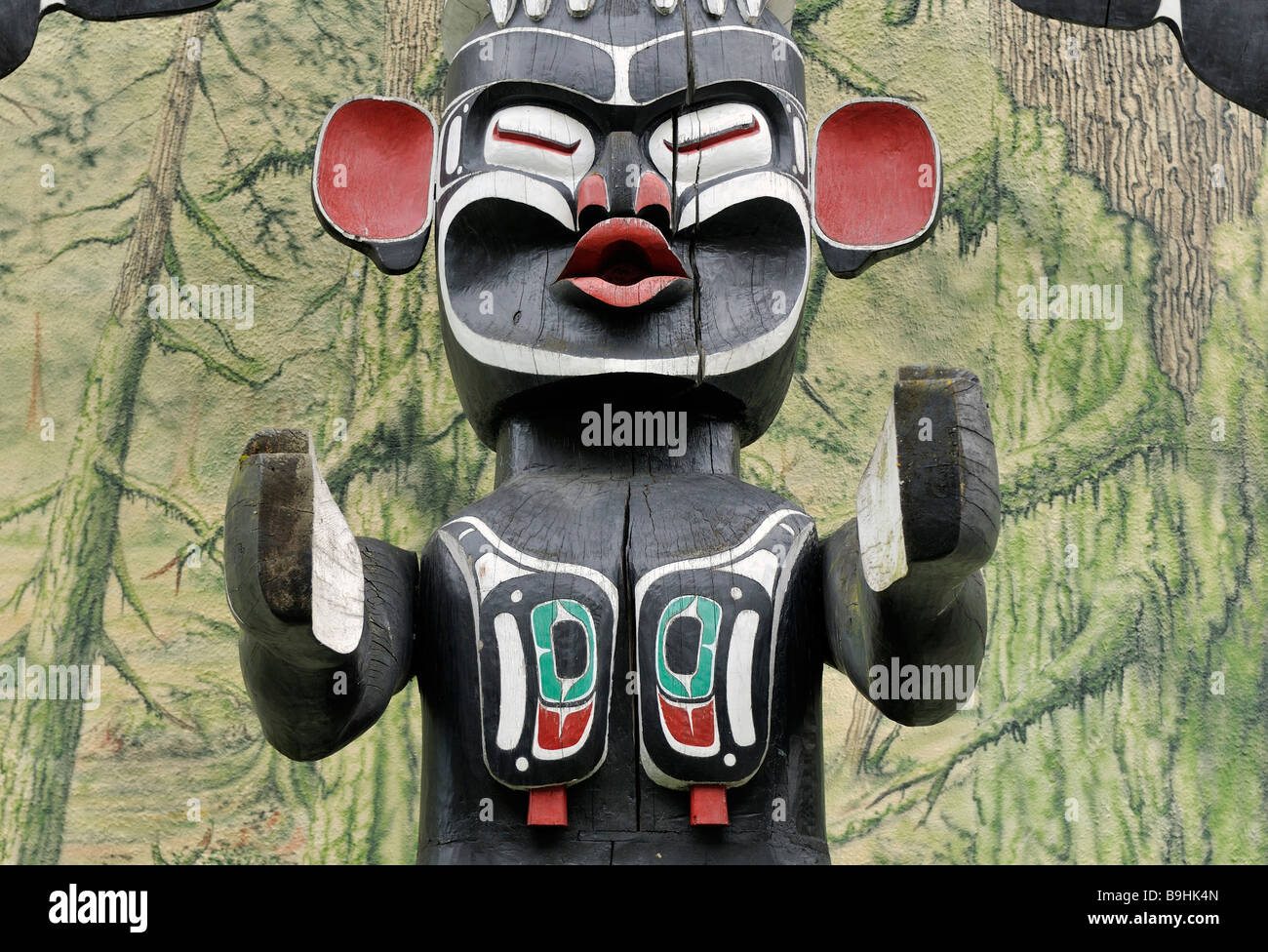 Il totem pole di Cowichan indiani, close-up, di fronte a una casa dipinta di parete, Duncan, Isola di Vancouver, Canada, America del Nord Foto Stock