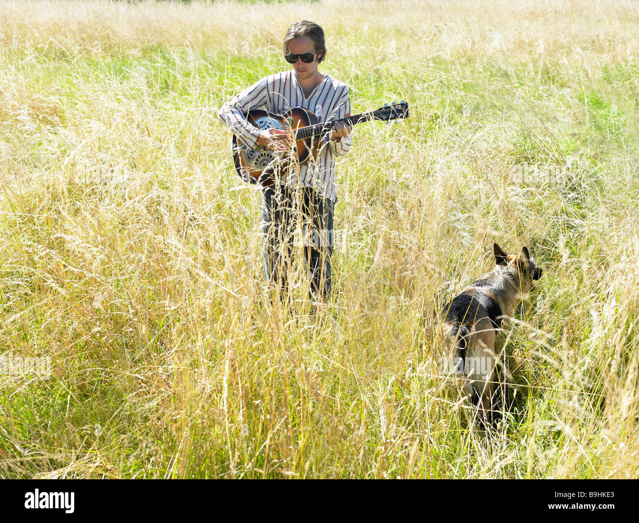 Uomo a suonare la chitarra in un campo Foto Stock