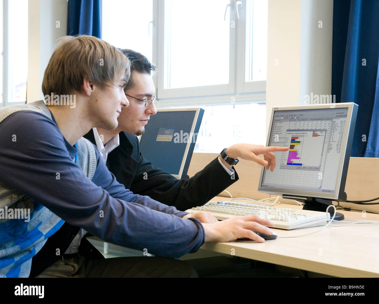 Gli adolescenti lavorando su un computer, usando grafici e tabelle Foto Stock