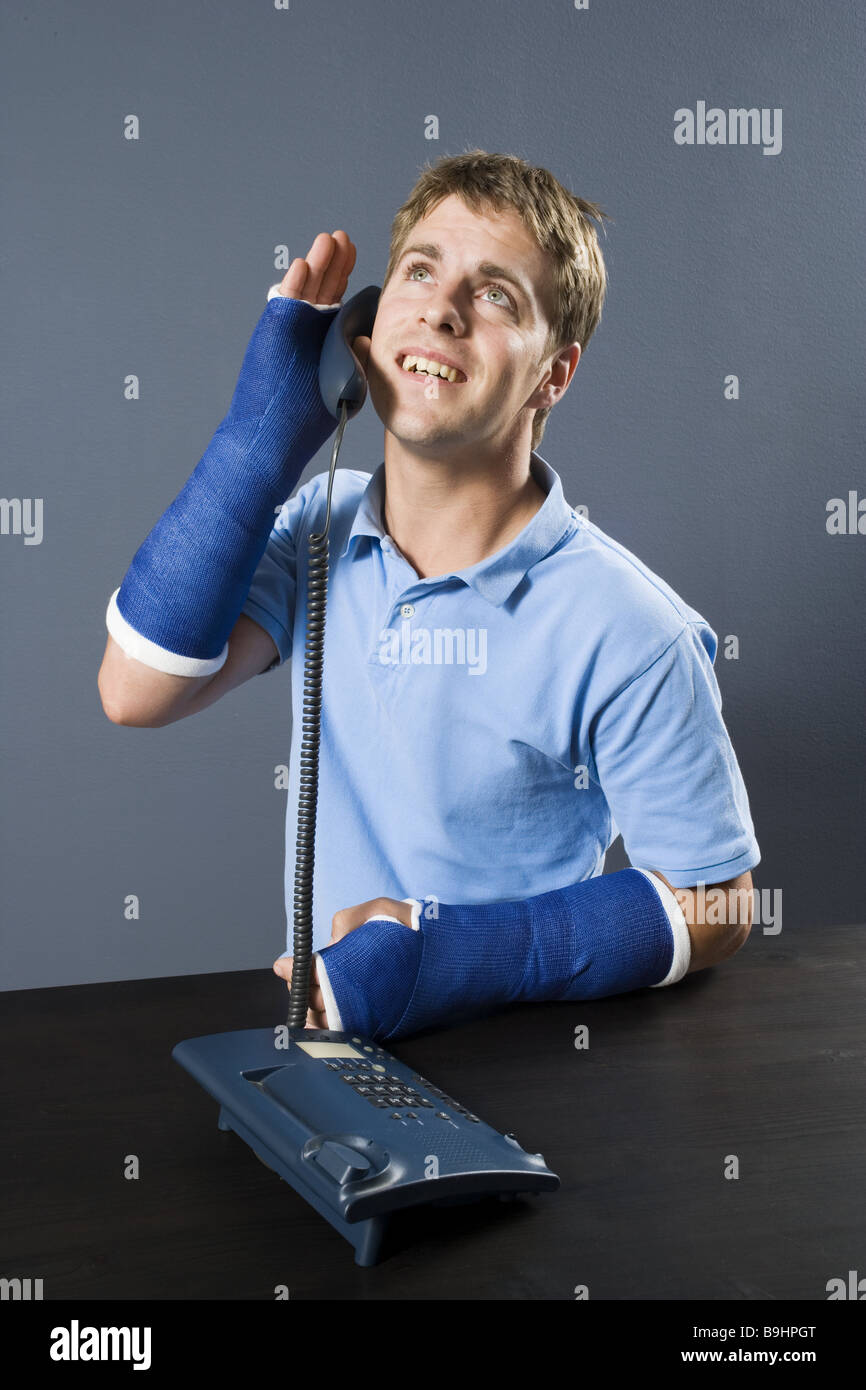 L'uomo dettaglio del braccio in gesso sorridente telefoni semi-ritratto persone serie lesioni del braccio fratture braccio-breaks intonacato in gesso Foto Stock