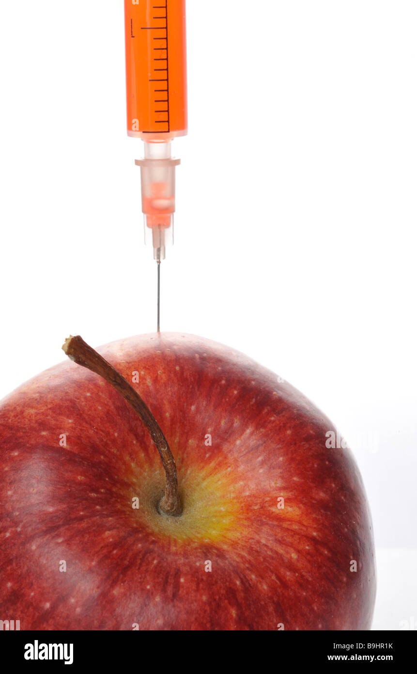 Ago di iniezione in un apple, immagine simbolica per gli alimenti geneticamente modificati Foto Stock