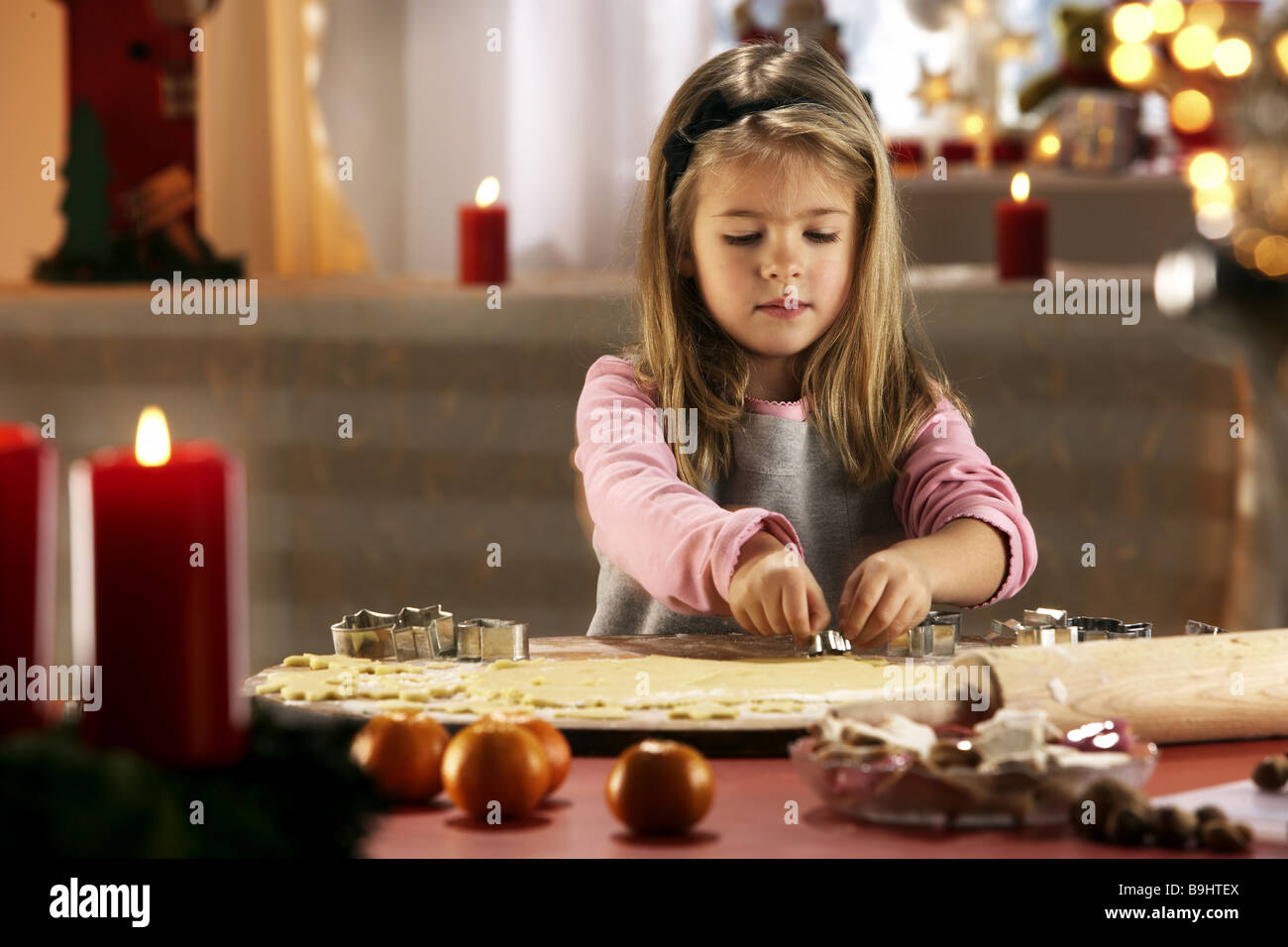 Ragazza di Natale taglierine cuocere pasta candele luoghi semi-ritratto serie tempo di Natale Avvento persone 5-7 anni bionda con i capelli lunghi Foto Stock