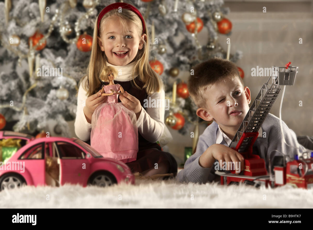 Natale fratelli tappeto sta seduta gioca giocattolo Natale sfondo-tree sfocatura serie persone i bambini 5-7 anni due ragazza Foto Stock