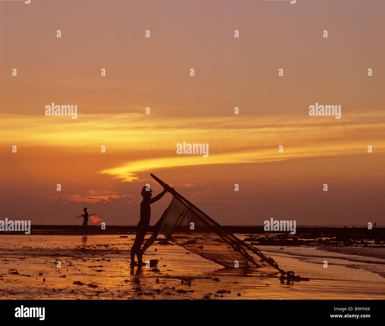 Pescatore con un net, oceano, luce della sera, Bali, Indonesia, sud-est asiatico Foto Stock