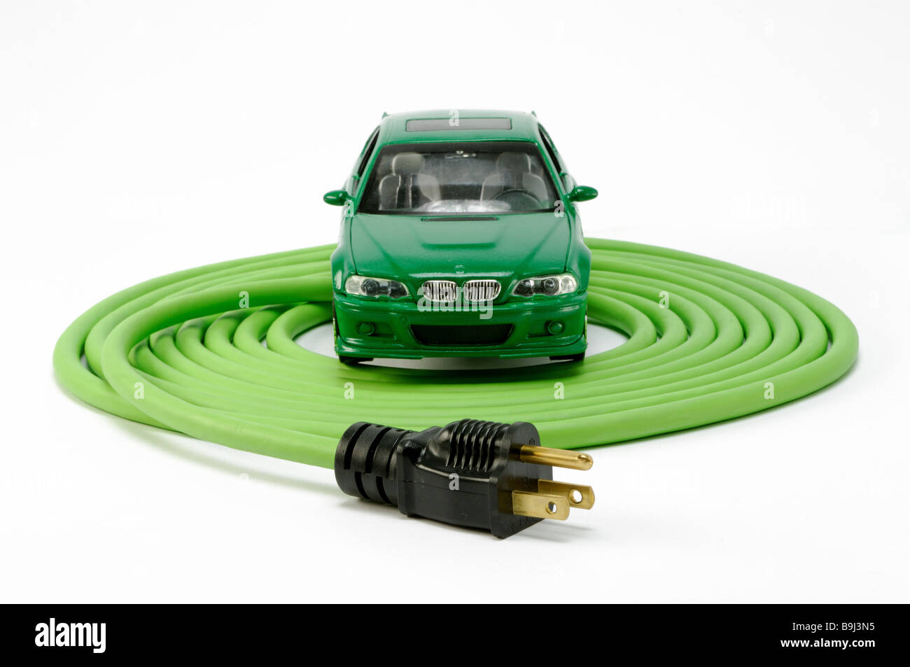 Un verde automobile automobile su un verde avvolto a spirale prolunga elettrica cavo di alimentazione con una spina Foto Stock